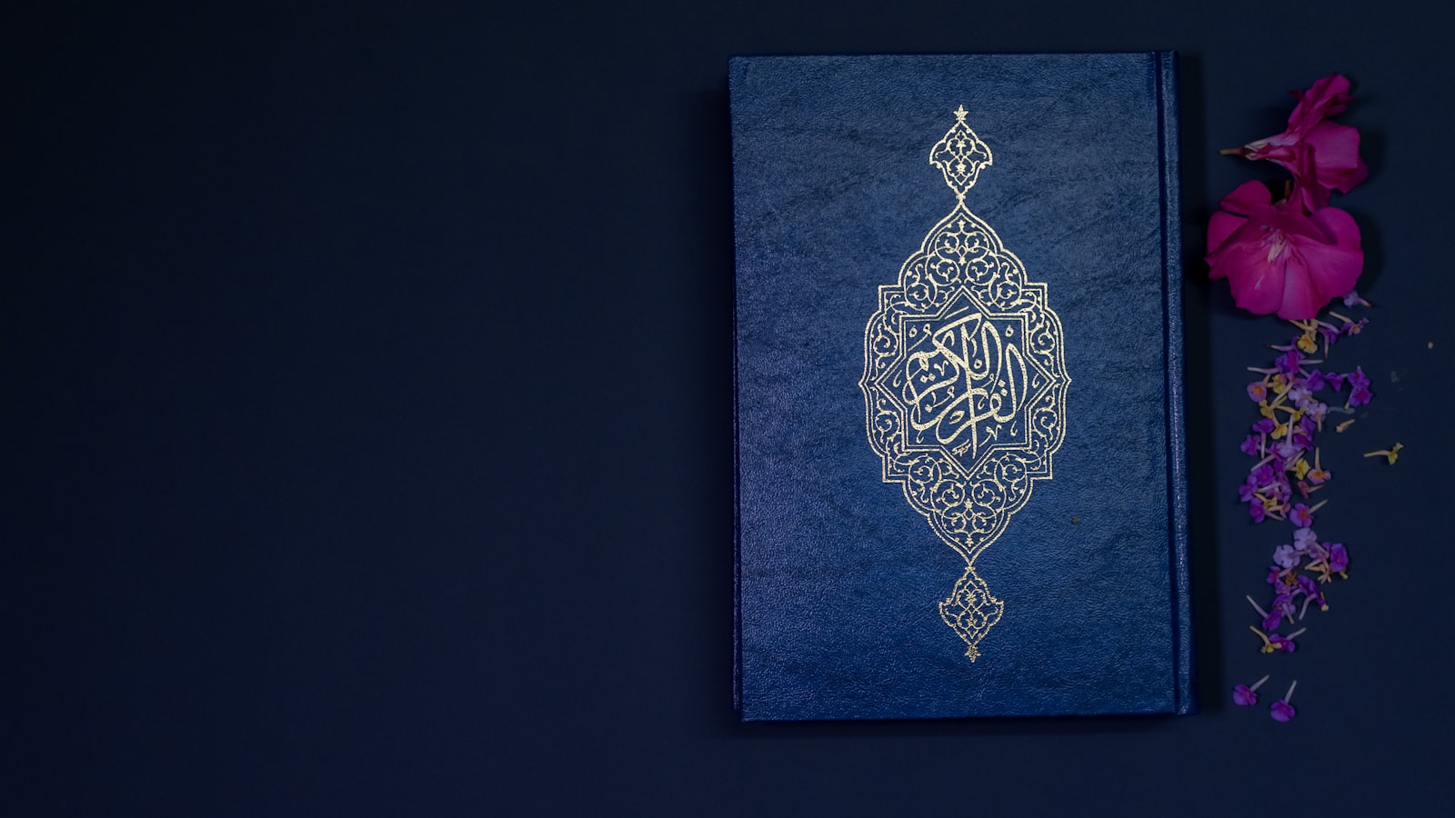 A Quran with delicate gold calligraphic detail on a deep navy background