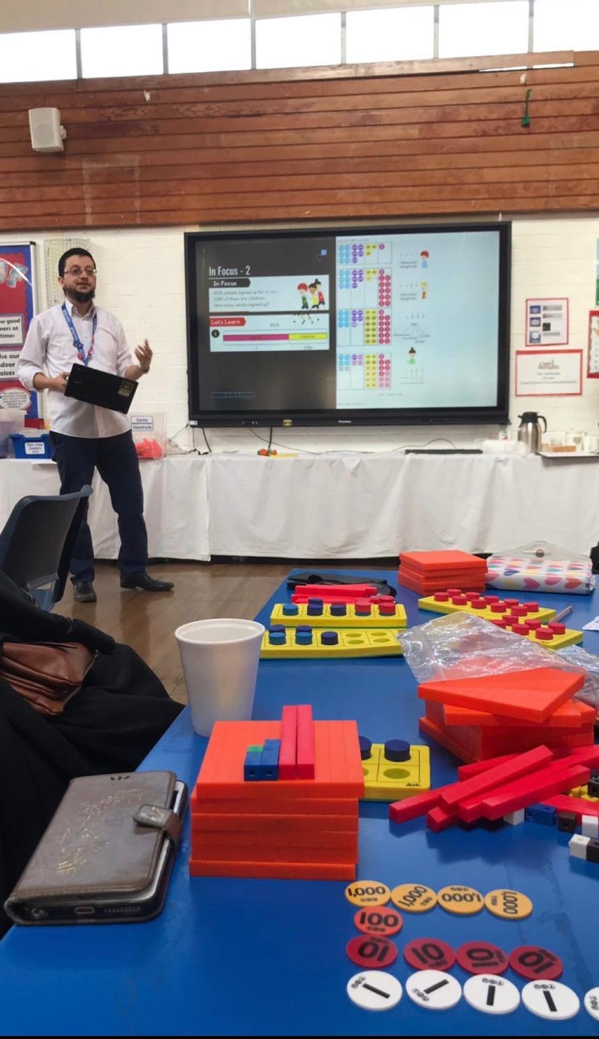 Ust. Bas leading a parent seminar on the Maths No Problem approach, smartboard showing an In Focus question with Numicon and Dienes manipulatives on the table