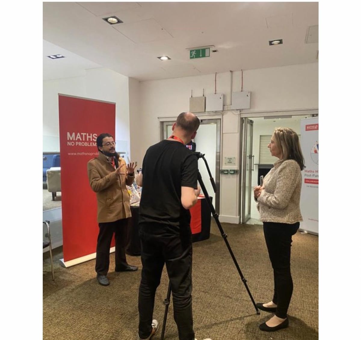 Ust. Bas being filmed for an interview at a Maths No Problem educators' conference, beside a Maths No Problem banner